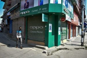 man wears a face mask, walks past a closed shops in India