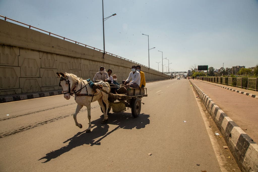 Indians travel on a horse drawn vehicle on a deserted road as a nationwide lockdown continues