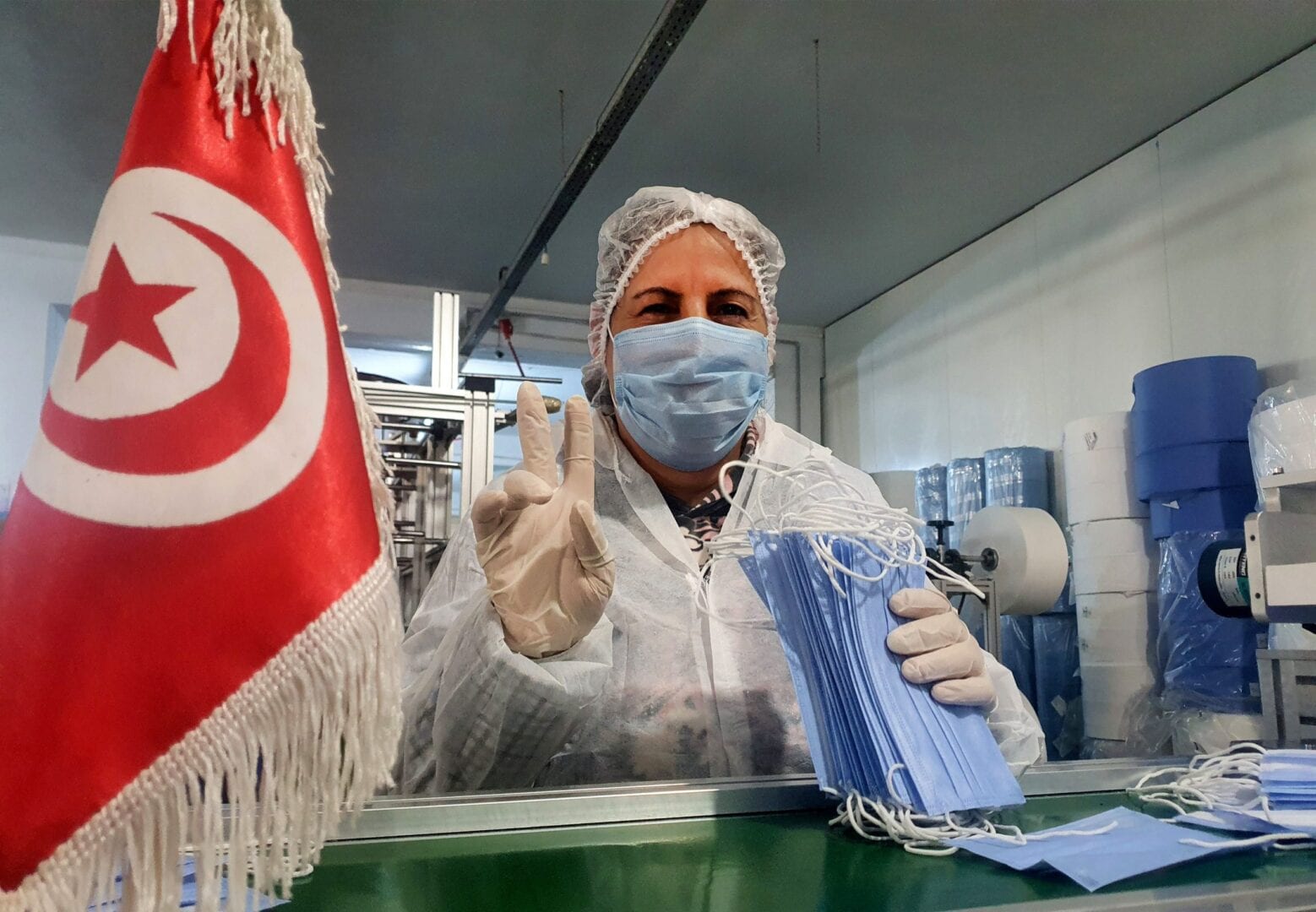A handout picture provided by the Consomed company for medical products on March 26, 2020, shows a Tunisian woman flashing the victory sign as she works on the production of medical masks in the company's factory in the central city of Kairouan.