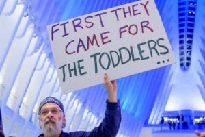 Man holds a sign that reads "First they came for the toddlers"