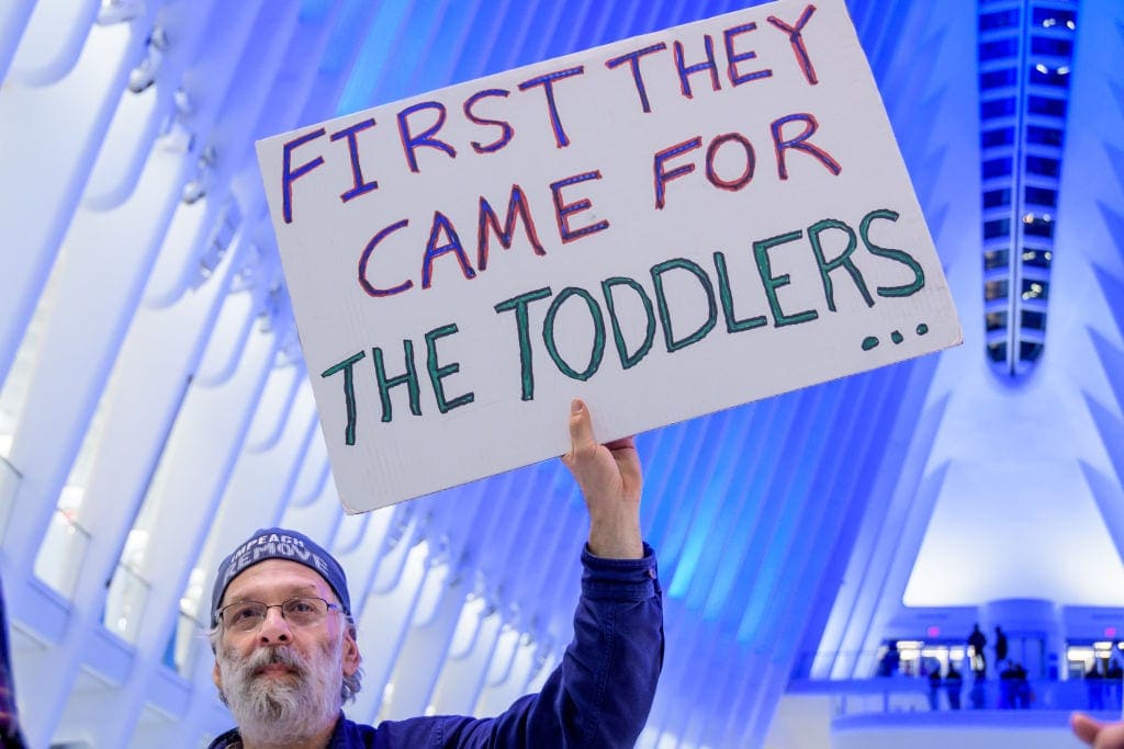 Man holds a sign that reads 