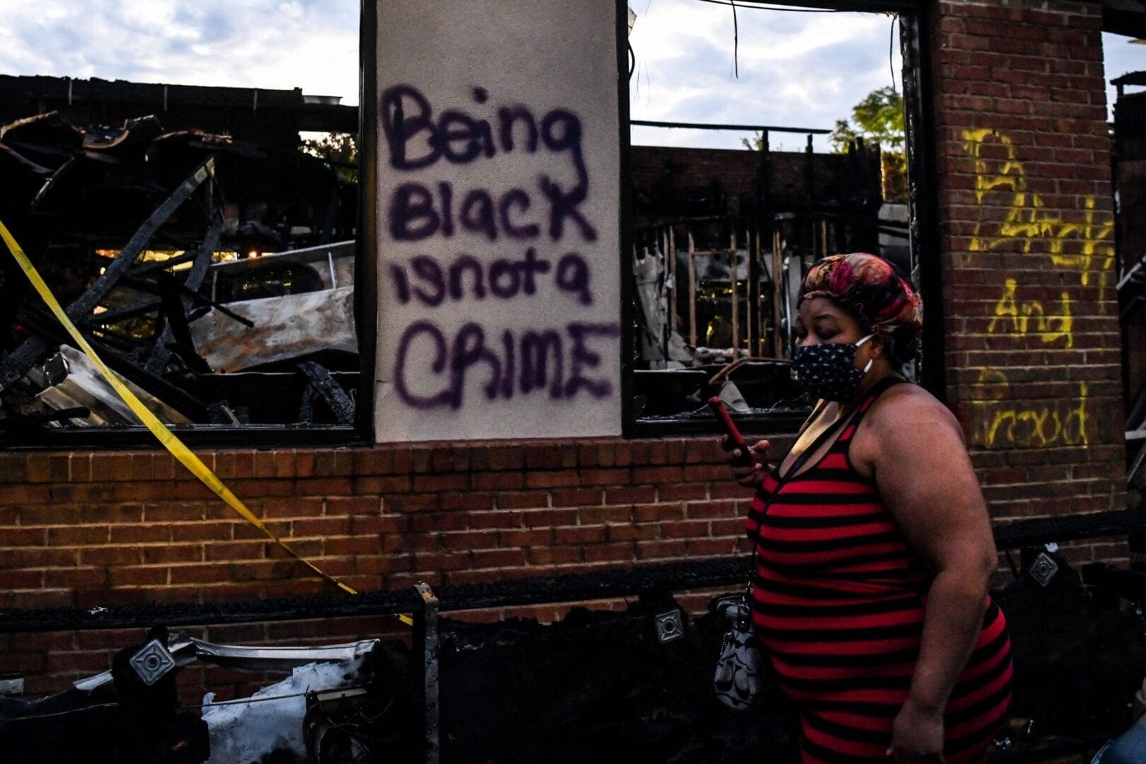 Woman walks past a wall on which graffitti reads 