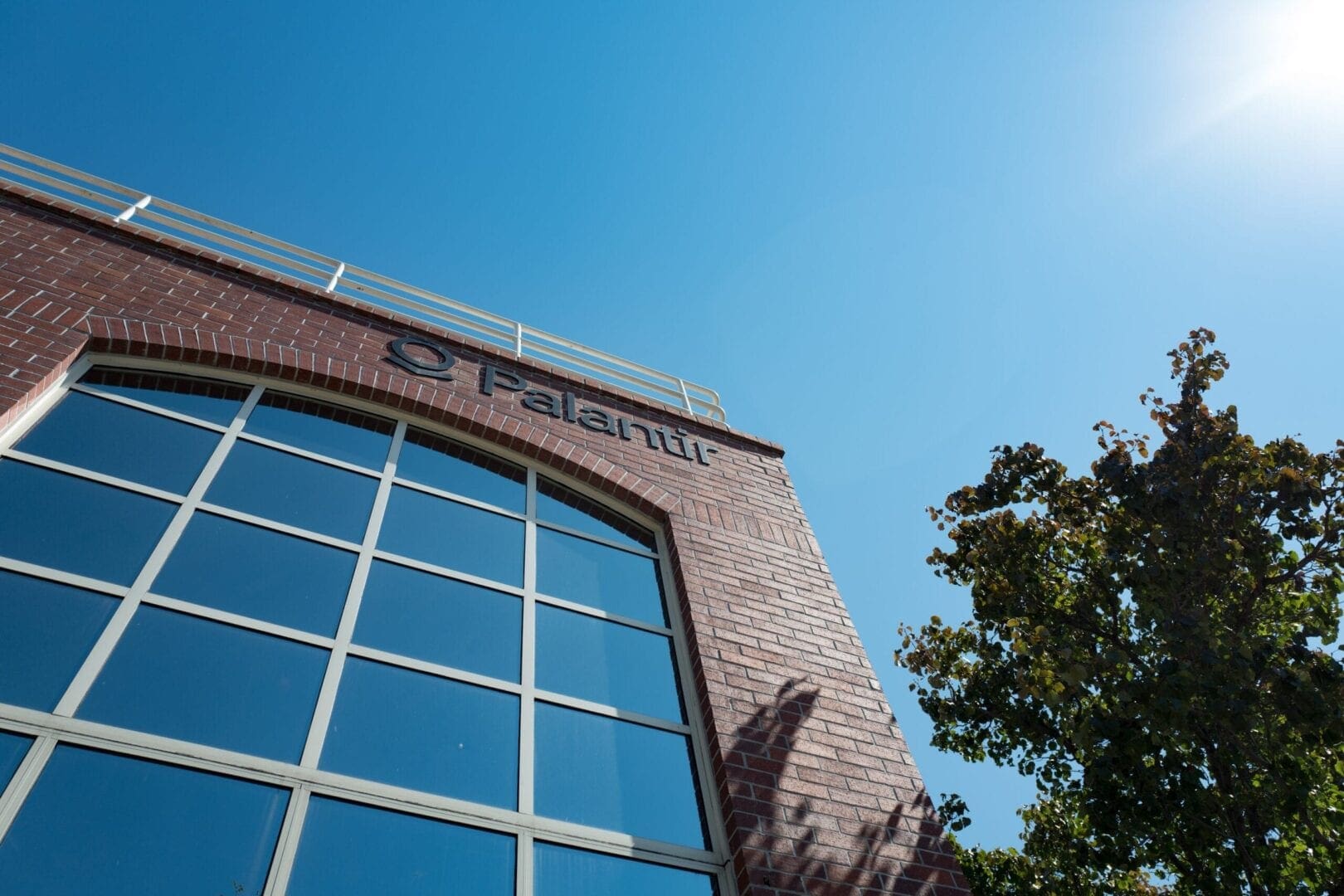 Side of a building with the word Palatir written across from it, with the sky in the background