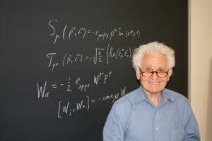 Person smiling standing in front of chalk board with equations