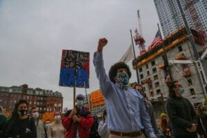 A protestor marches with others, with a fist in the air