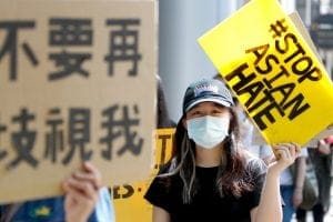 A woman holds a sign that reads: Stop Asian Hate
