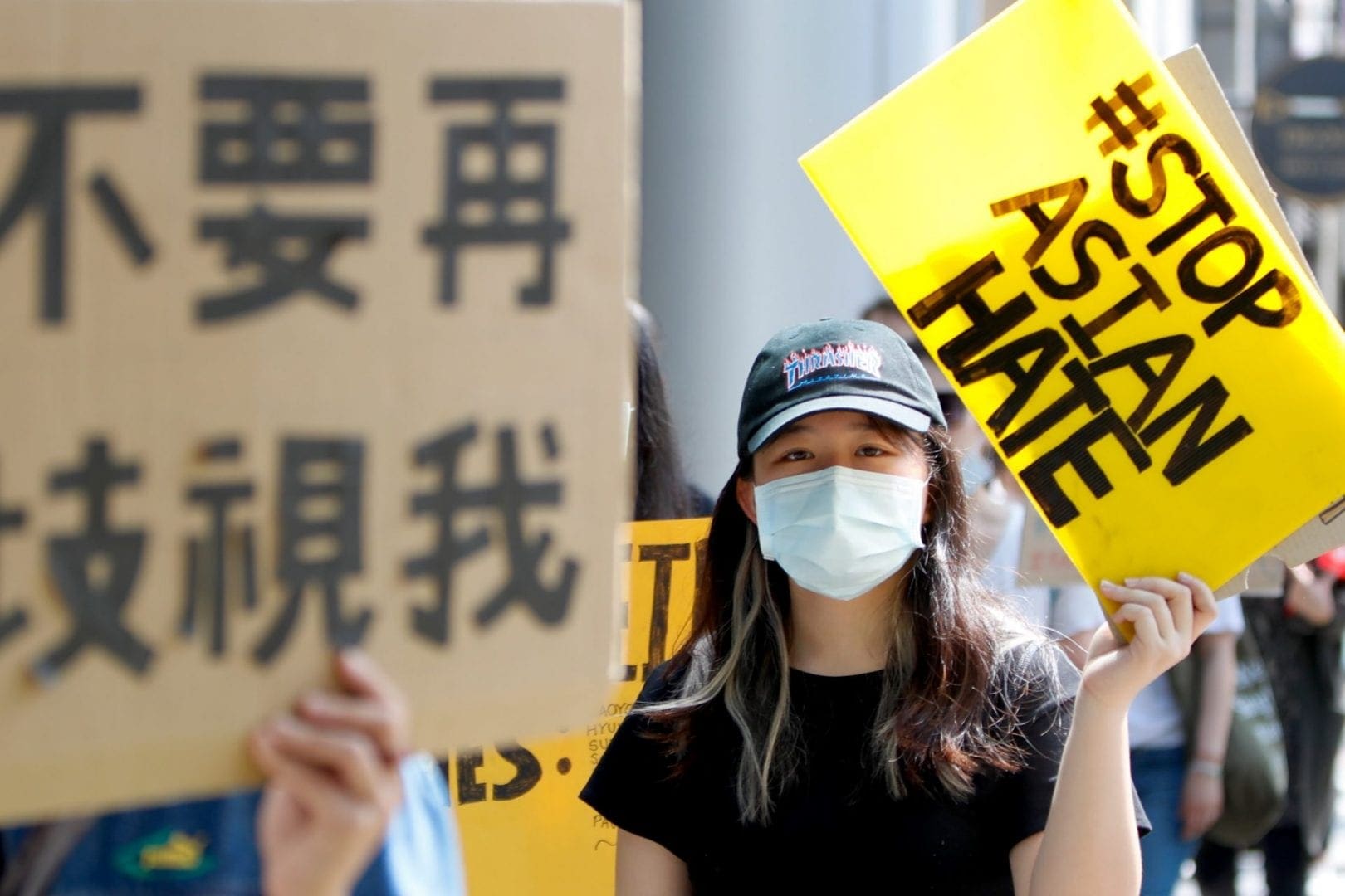 A woman holds a sign that reads: Stop Asian Hate