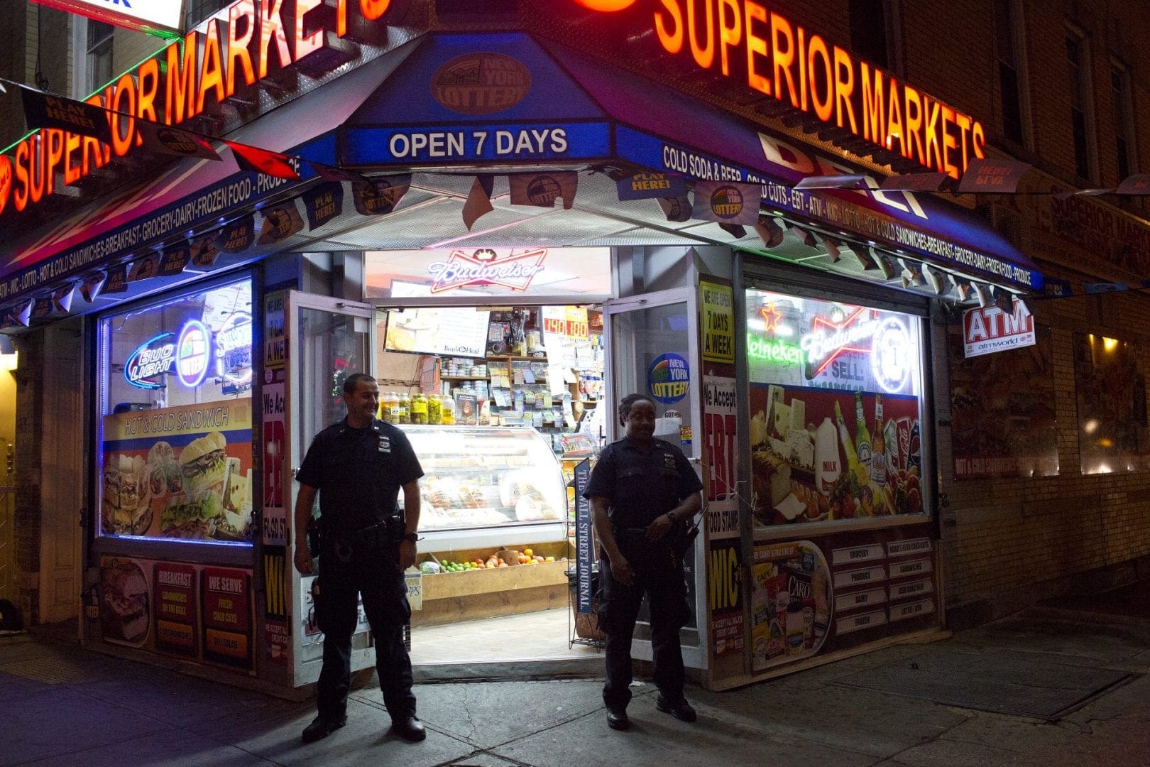 Police officers stand in front of deli at night