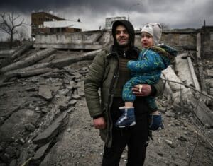 A man holding a boy in a war affected area