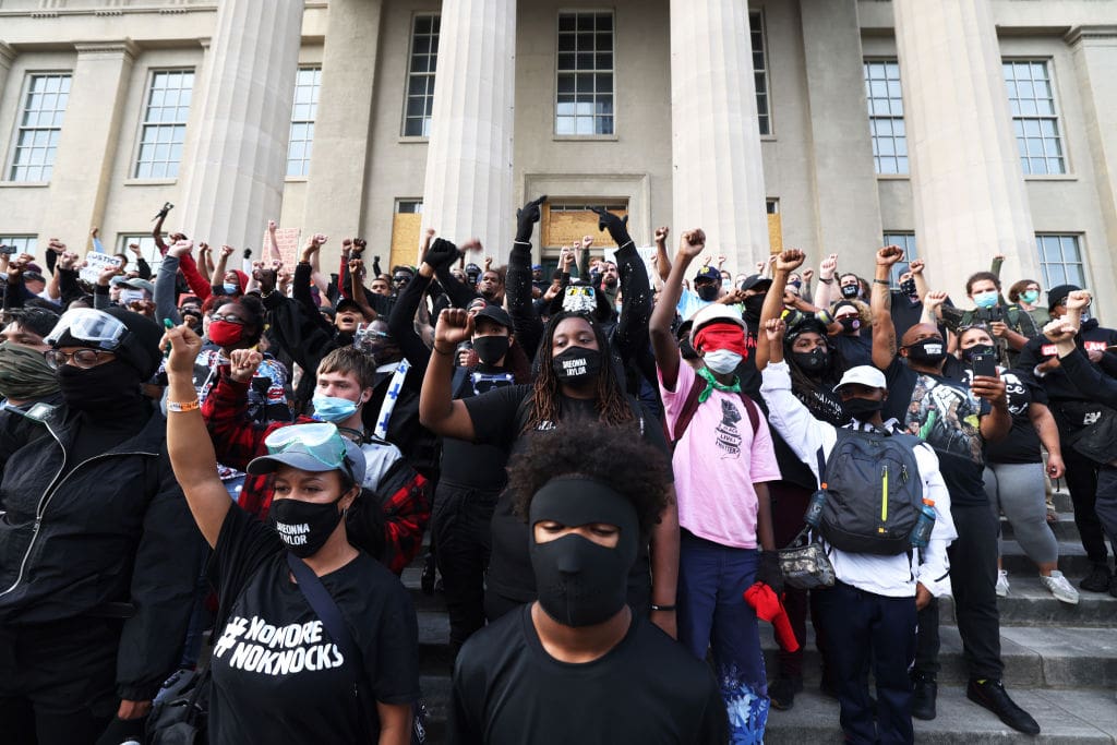 LOUISVILLE, KENTUCKY - SEPTEMBER 24: Demonstrators raise their fists as they gather on the steps of the Louisville Metro Hall on September 24, 2020 in Louisville, Kentucky. A Kentucky grand jury indicted one police officer involved in the shooting of Breonna Taylor with three counts of wanton endangerment. No officers were indicted on charges in connection to Taylor's death. (Photo by Michael M. Santiago/Getty Images)