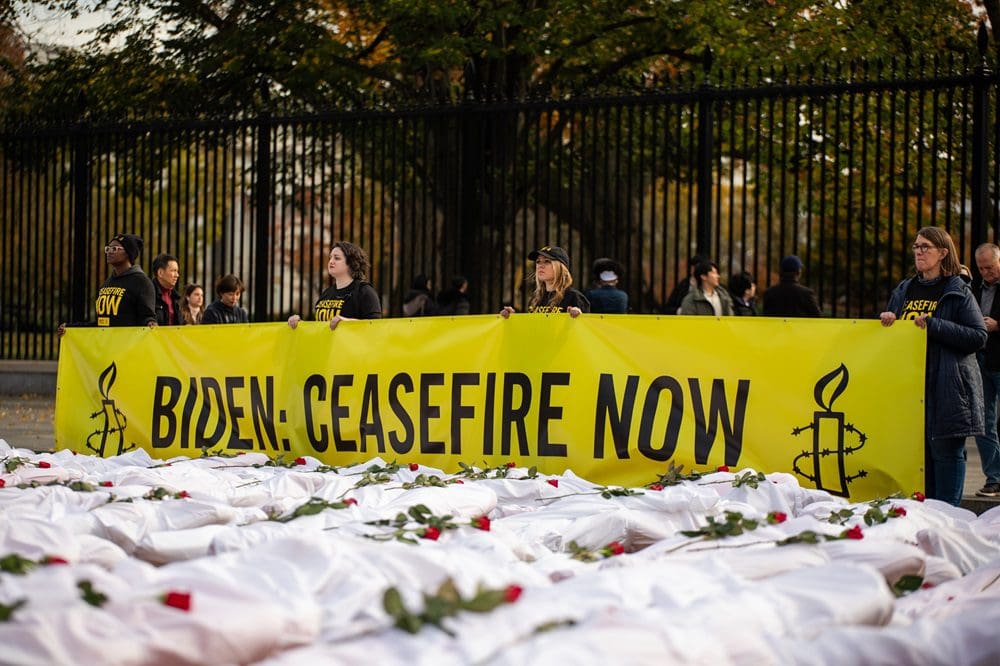 Amnesty International USA staff and members hold Biden Ceasefire Now banner at White House