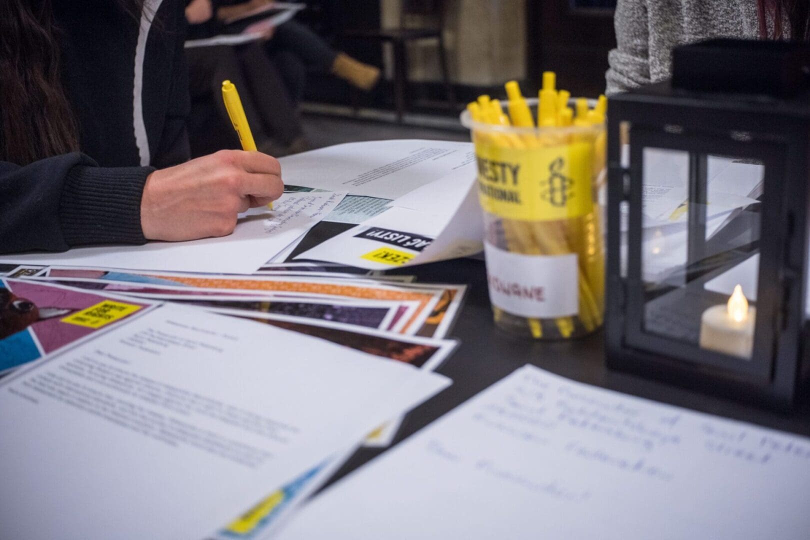 Hands writing on papers on desk