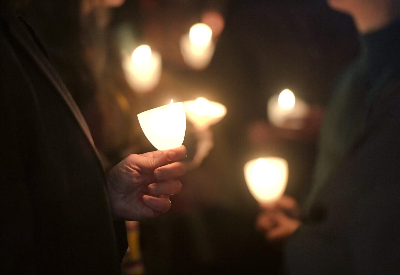 People stand outside holding candles in Kristallnacht remembrance ceremony