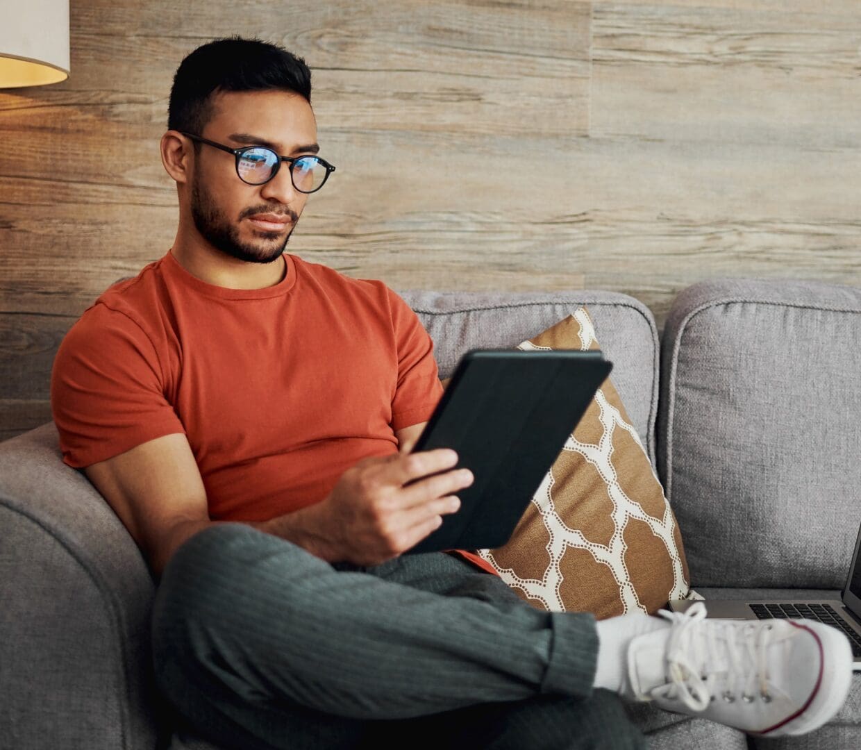 young man sitting alone in his living room and using a digital tablet