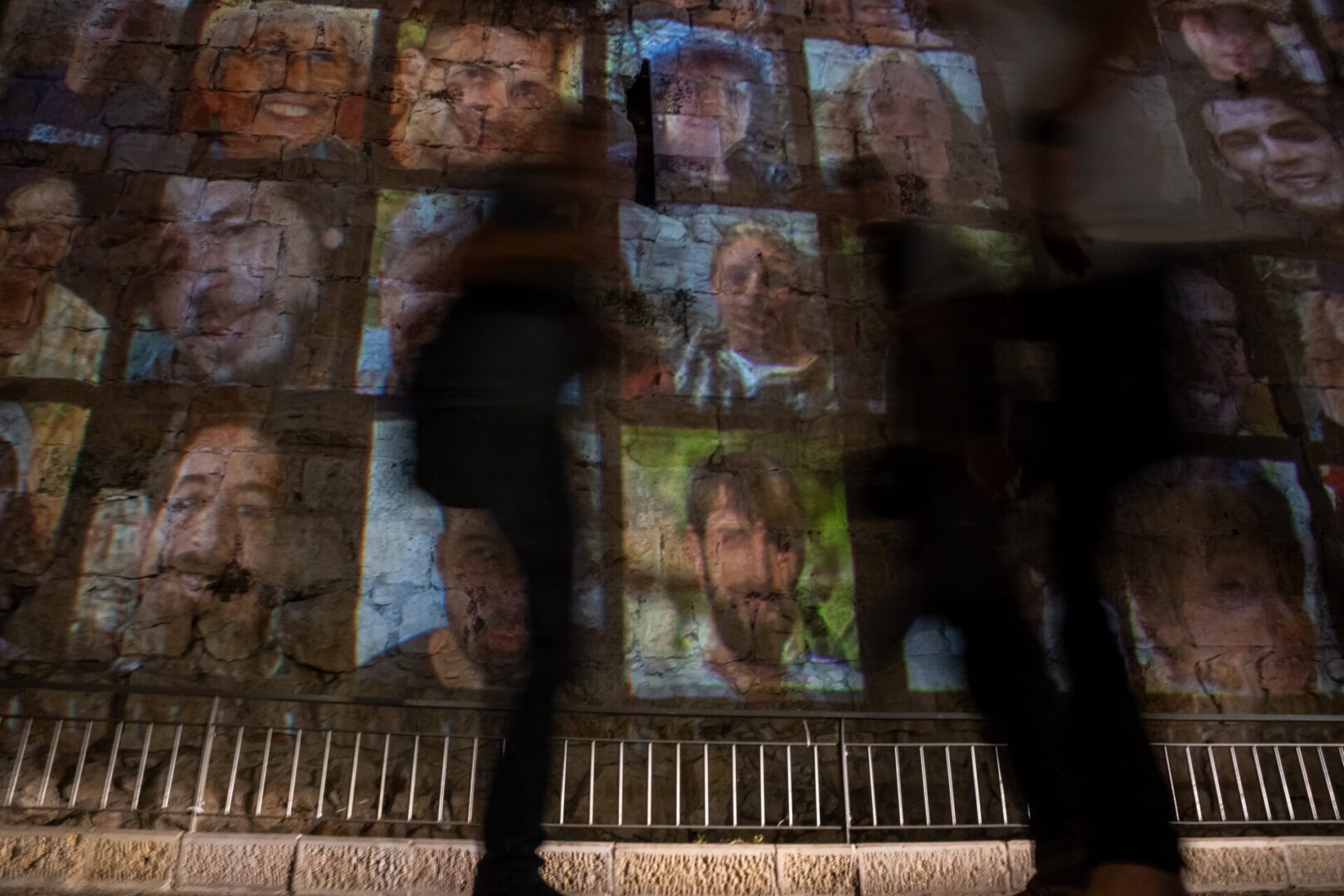 People walk past faces of hostages projected on the walls of the Old City neat the Jaffa Gate on November 06, 2023 in Jerusalem.