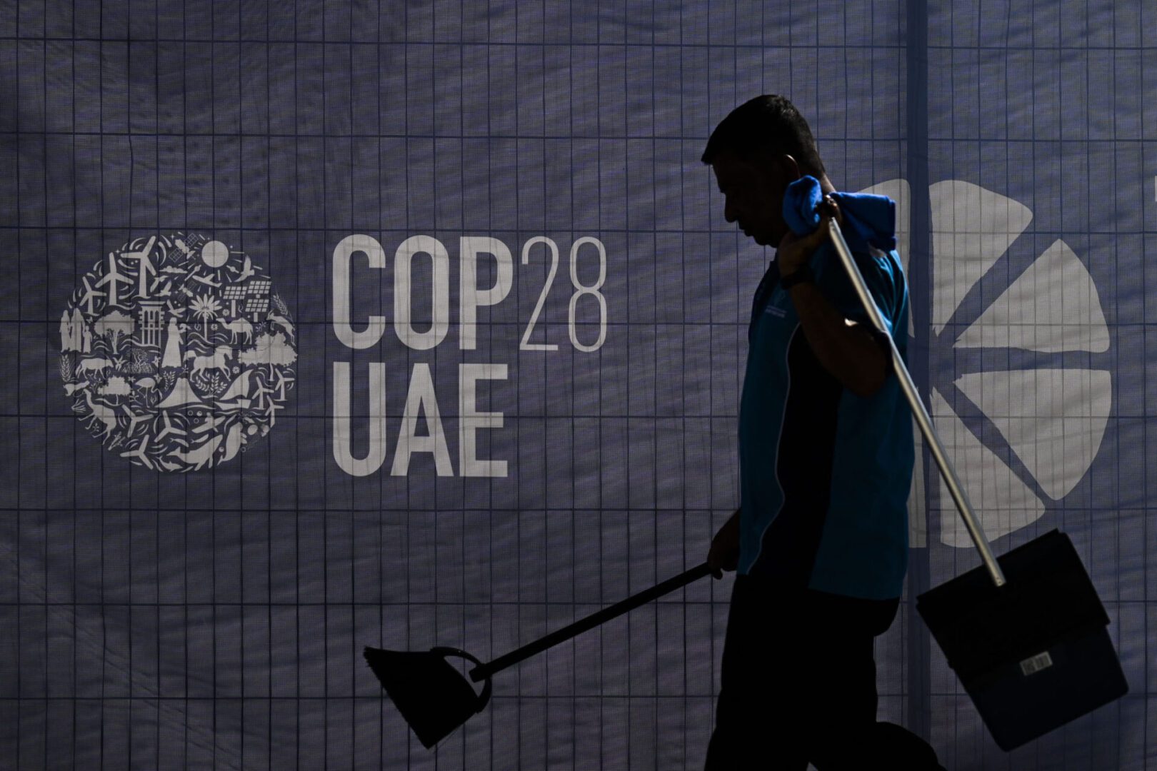 A worker walks past a COP28 logo ahead of the United Nations climate summit in Dubai on November 28, 2023. The UN chief urged world leaders to take decisive action to tackle ever-worsening climate change when they gather at the COP28 summit in Dubai starting this week. (Photo by Jewel SAMAD / AFP) (Photo by JEWEL SAMAD/AFP via Getty Images)