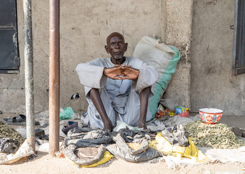 An older man sits and waits to sell food at a market near Maiduguri, Borno State, northeastern Nigeria.