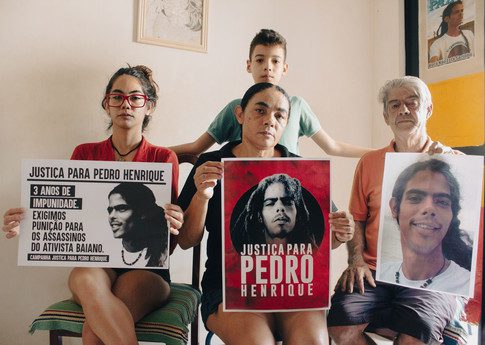 Family of Pedro Henrique Santos Cruz with placards demanding justice for Pedro (from left to right: sister of Pedro, grandchild of Ana Maria and Pedro's cousin, Ana Maria - Pedro's moher, and Pedro's father). Henrique Santos Cruz, 31 years old, a young black man, human rights defender, that was widely recognized as an activist in the field of confronting police violence and the promotion of racial justice. After being the victim of violence in a police approach in front of his father's house, in 2012, Pedro became the organizer of the so-called “Walks of Peace”, annual marches against police violence. These are like a “Black Lives Matter march”, which peacefully brought together teenagers, young people, adults and seniors from their community to claim for justice and the end of police violence towards Black population. On 27 December 2018, Pedro Henrique was killed, aged 31. His house was raided by three hooded men as he slept next to his girlfriend. He was shot eight times in the head and neck. His girlfriend recognized the three men as police officers. The officers suspected of killing Pedro Henrique were indicted in 2019. But almost five years on, they are still active in the police force. The investigation into the killing has not been concluded and the trial has yet to begin. Despite ongoing threats and the grief of losing her son, Ana Maria has bravely sought the truth about his death, calling on the authorities for a thorough investigation and trial.