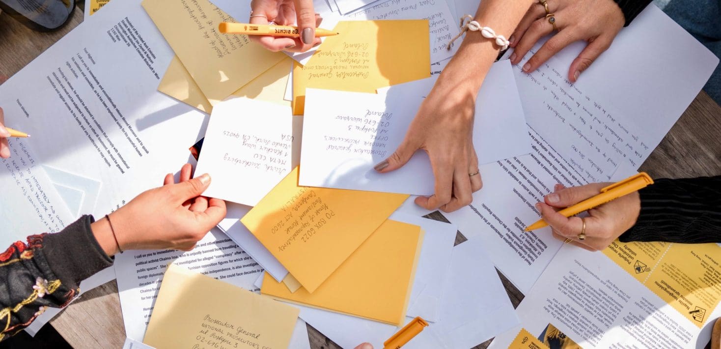 People writing on a pile of letters for Amnesty International's Write for Rights campaign