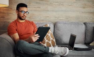 Shot of a handsome young man sitting alone in his living room and using a digital tablet