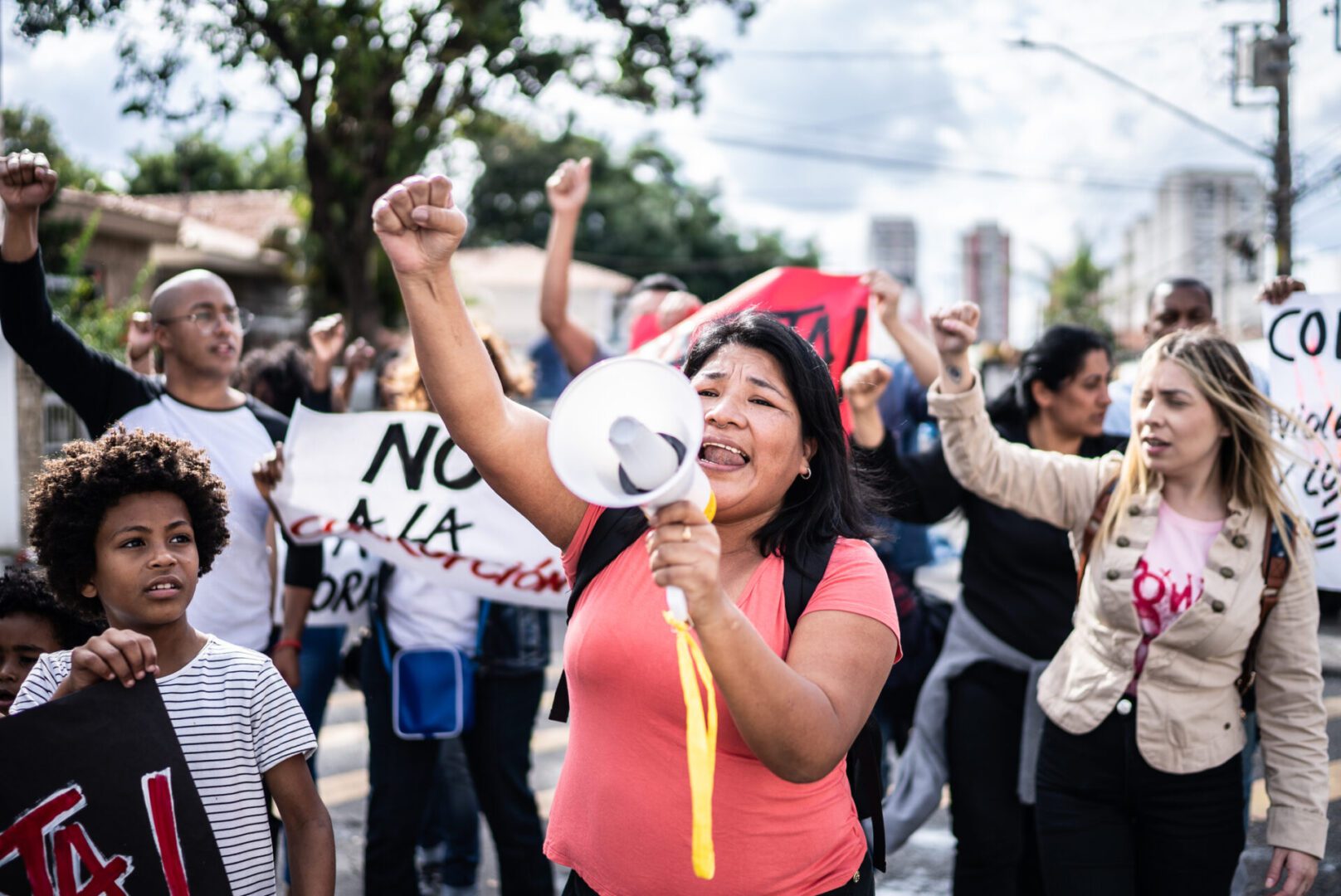 Hispanic woman talking in a megaphone during a protest in the street