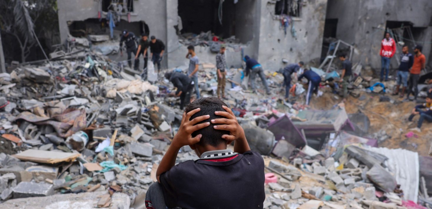 young boy in front of destroyed building in Gaza