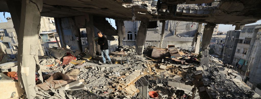 man looks over a destroyed building in Gaza