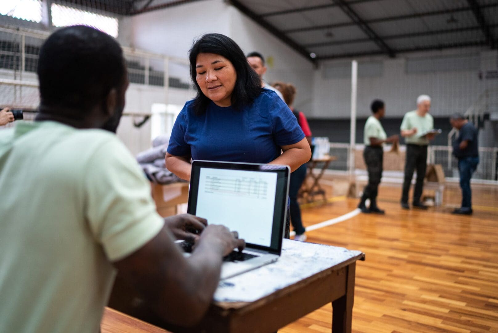 Volunteer talking with a refugee woman while using the laptop at a refugee sheltering