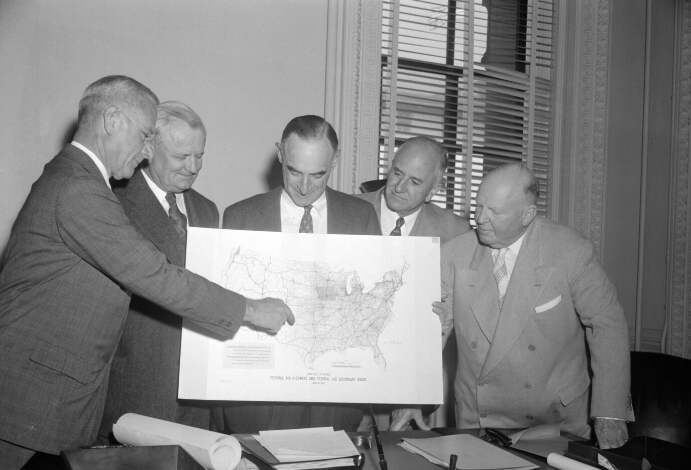 Members of a presidential committee began a conference yesterday with business and industrial leaders to map plans for carrying out President Eisenhower's 10-year, 50 billion dollar highway construction program. Looking over a chart (from left): S. Sloan Colt, president of Bankers Trust Company of New York; William A. Roberts, president of Allis Chalmers Company, of Milwaukee, Wisconsin; General Lucius D. Clay, chairman of the president's committee on the National Highway Program; Stephen Bechtel, president of the Bechtel Corporation of San Francisco; and David Beck, president of the International Brotherhood of Teamsters in Seattle, Washington.