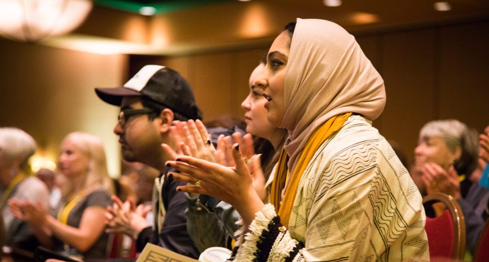 Row of people including a Muslim woman clapping