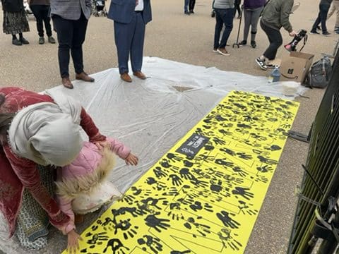 woman and child put their handprints on Let Gaza Live banner