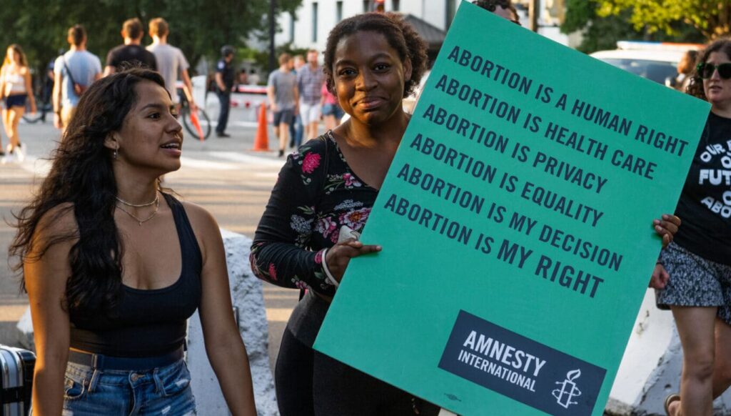 Two AIUSA volunteers holding a sign at a protest.