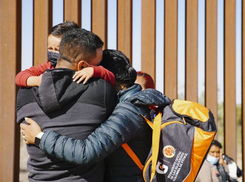 YUMA, ARIZONA, UNITED STATES - FEBRUARY 21: Asylum seekers embrace, next to the USA border wall, while waiting to be processed by CBP on February 21, 2022 in Yuma, Arizona, United States. (Photo by Katie McTiernan/Anadolu Agency via Getty Images)