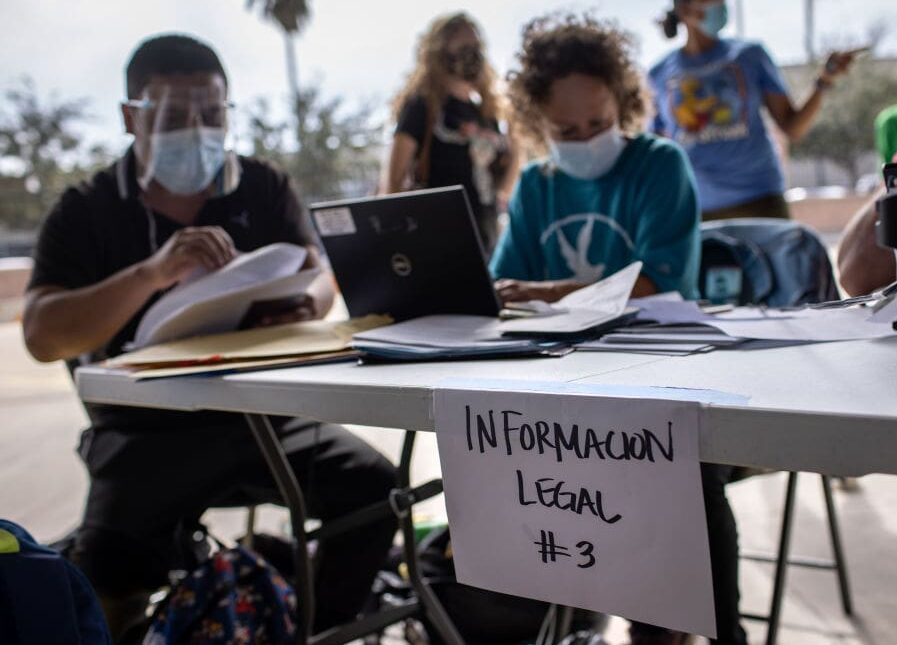 BROWNSVILLE, TEXAS - FEBRUARY 26: An attorney (C), assists immigrants with asylum documentation on February 26, 2021 in Brownsville, Texas. The group was one of the first to cross into south Texas as part of the Biden administration's unwinding of the Trump-era Migrant Protection Protocols, (MPP), also known as the 'Remain in Mexico' immigration policy. Many of the asylum seekers had been waiting in the squalid camp alongside the Rio Grande in Matamoros for more than a year. The immigrants are now free to travel to destinations within the United States pending asylum court hearings. (Photo by John Moore/Getty Images)