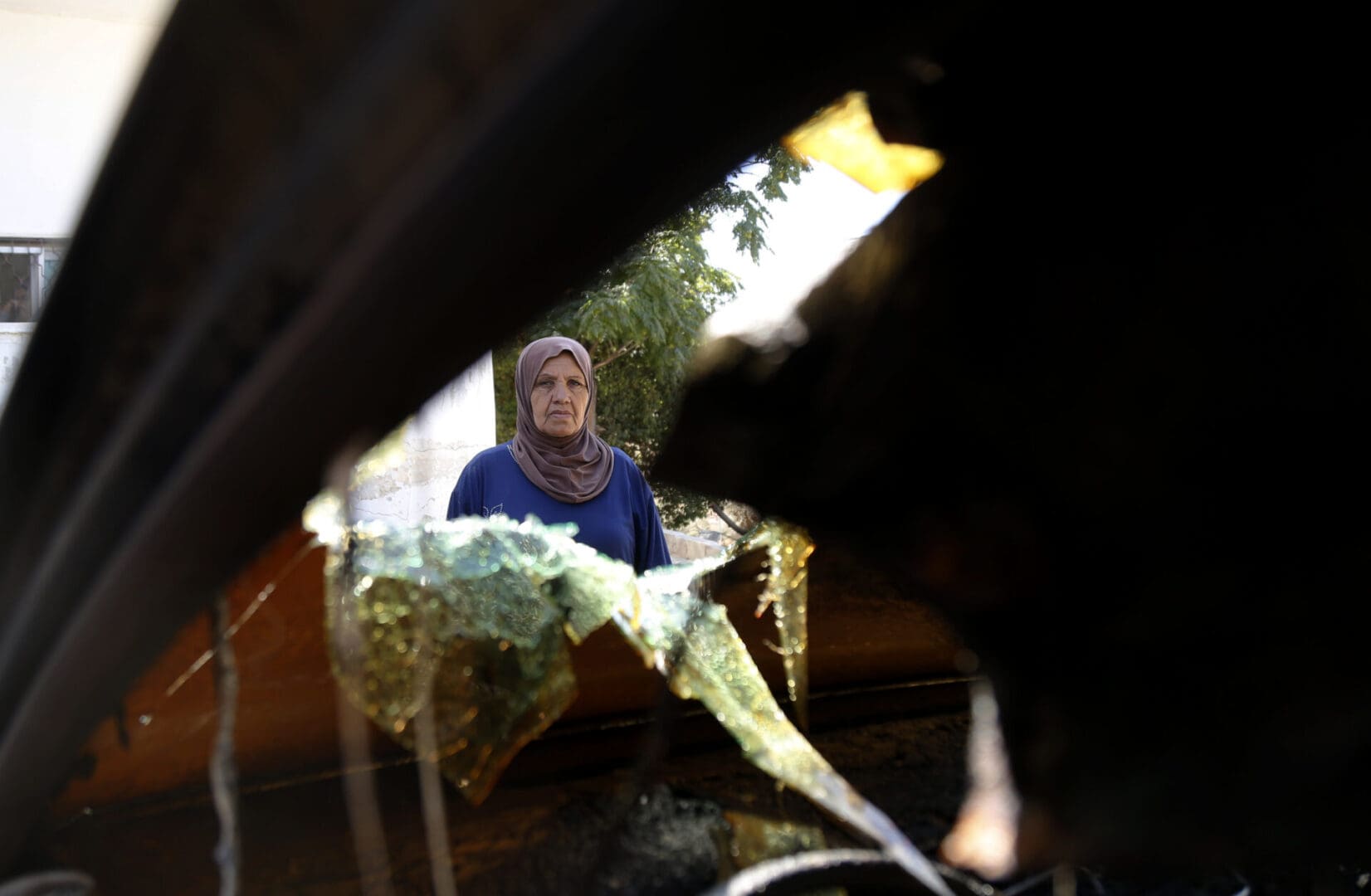 Palestinians look at the vehicles which were burnt down after an Israeli raid under the name of