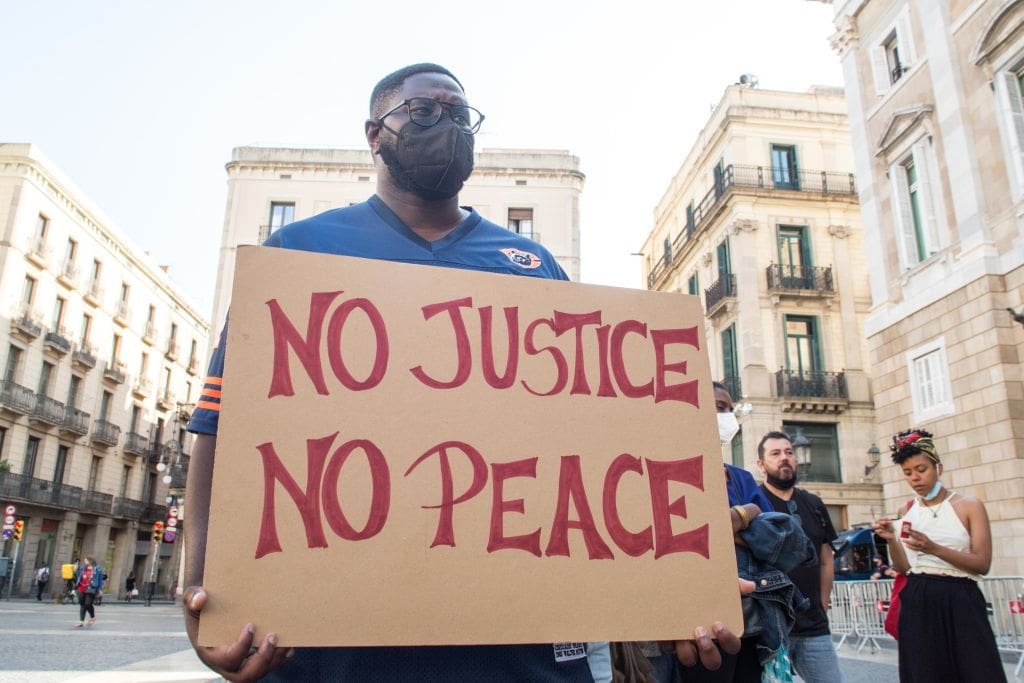 A protester holding a placard that reads, no justice no