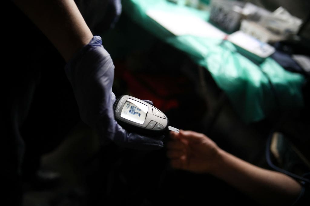 In Krakow, Poland, on December 22, 2024, a doctor checks blood sugar levels in a field hospital during the ''Christmas Eve for the Homeless and Needy'' event held at the Main Square. Each year, just before Christmas, a special Christmas Eve gathering is organized at the Main Square for those in need. During the event, warm traditional holiday meals are served, with the initiative organized and sponsored by Jan Koscioszko. Additionally, a field hospital is set up at the Main Square, providing professional medical assistance to those in need. (Photo by Klaudia Radecka/NurPhoto via Getty Images)