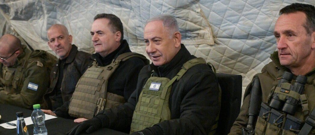Netanyahu sitting with men in military outfit.