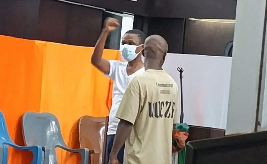 Man holding fist up in air while in detainment.