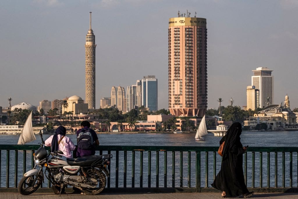 A veiled woman walks past a couple along the Cairo University bridge.