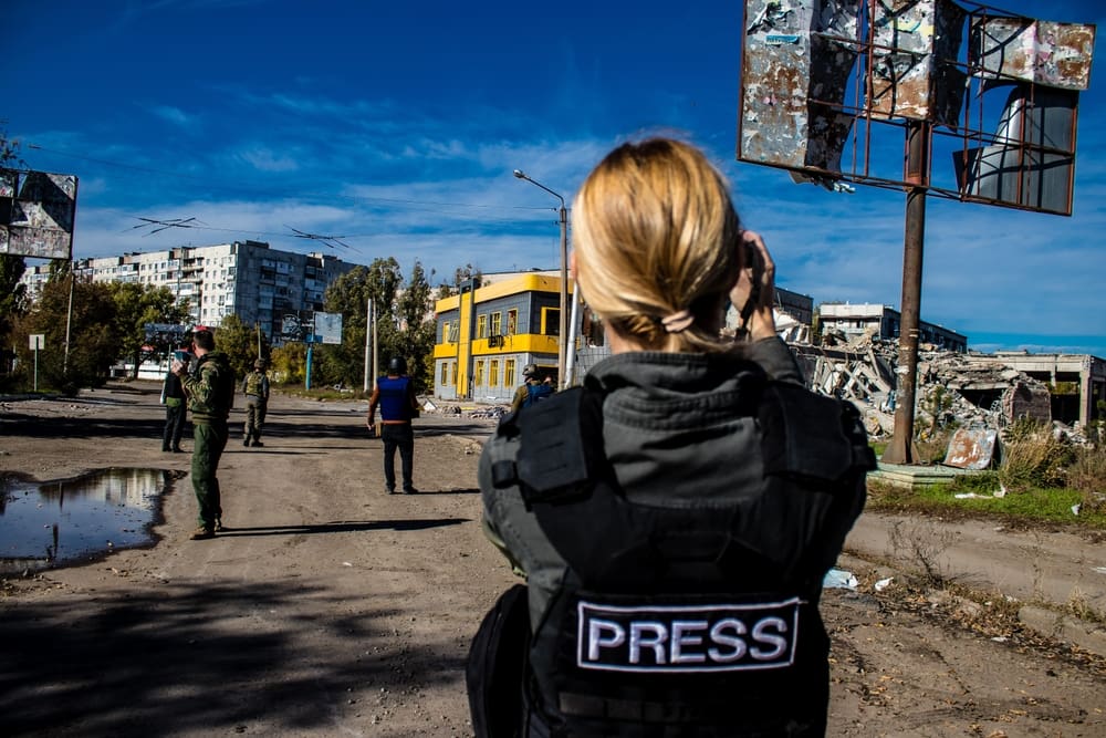photographer in press jacket takes pictures of Ukraine war