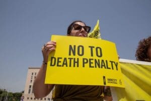 A woman holds up a yellow sign that says in black letters
