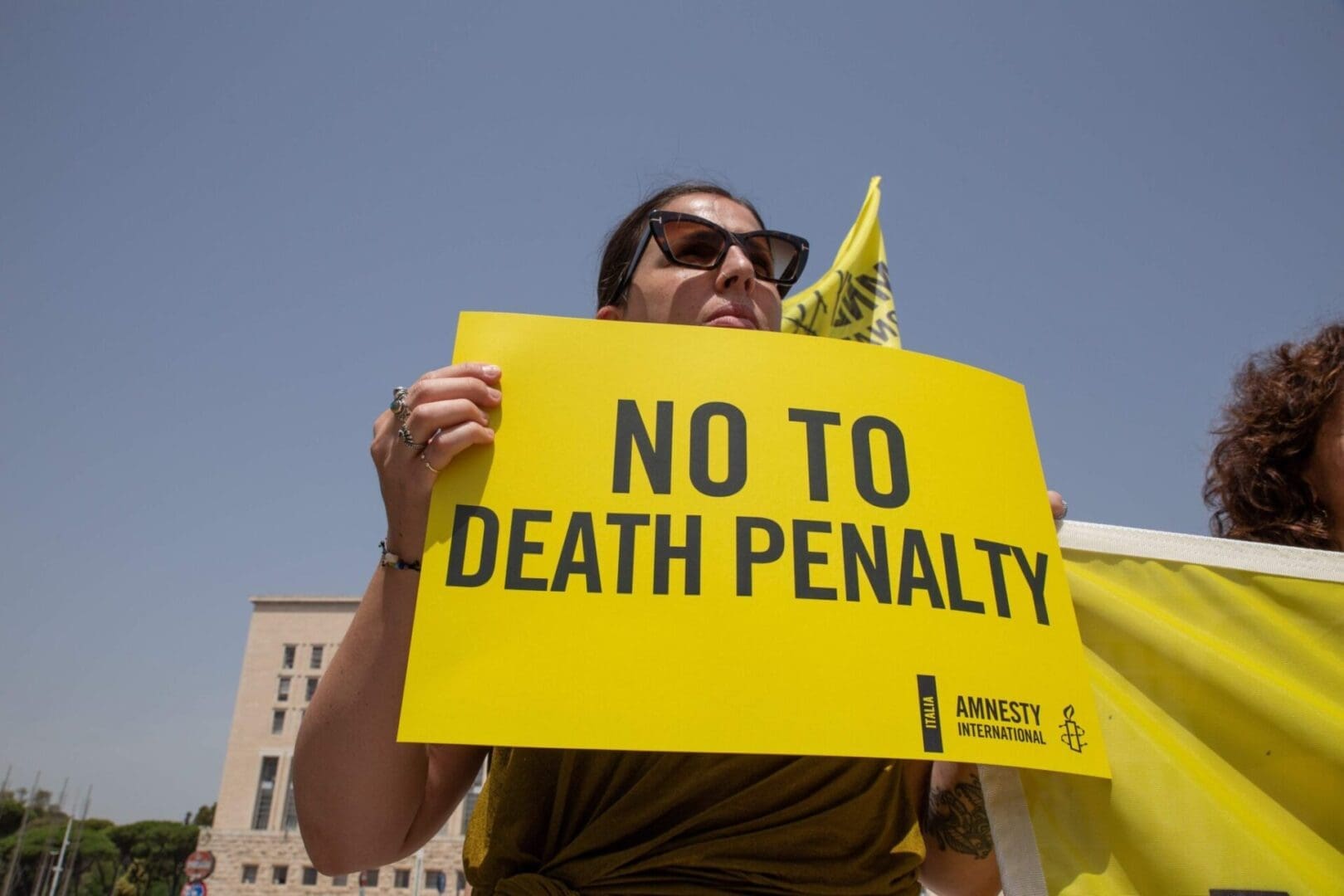 A woman holds up a yellow sign that says in black letters