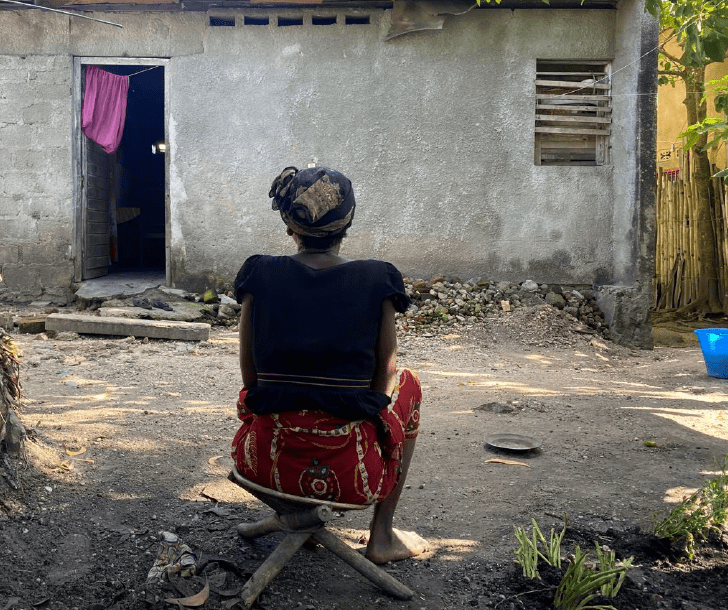 A Congolese woman sits in silence, gazing at her family’s shell-damaged home. She suffers from mental trauma since the war.