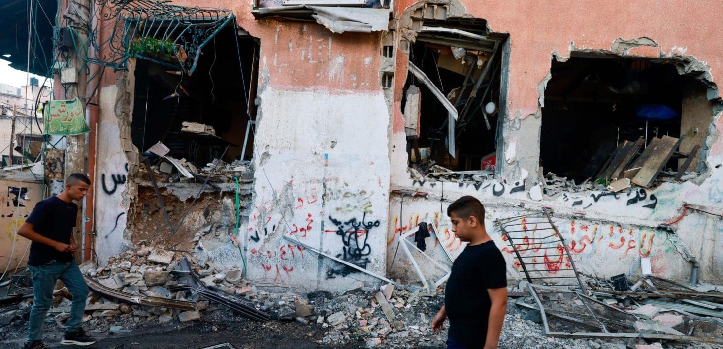 man walks past bombed out building in Gaza
