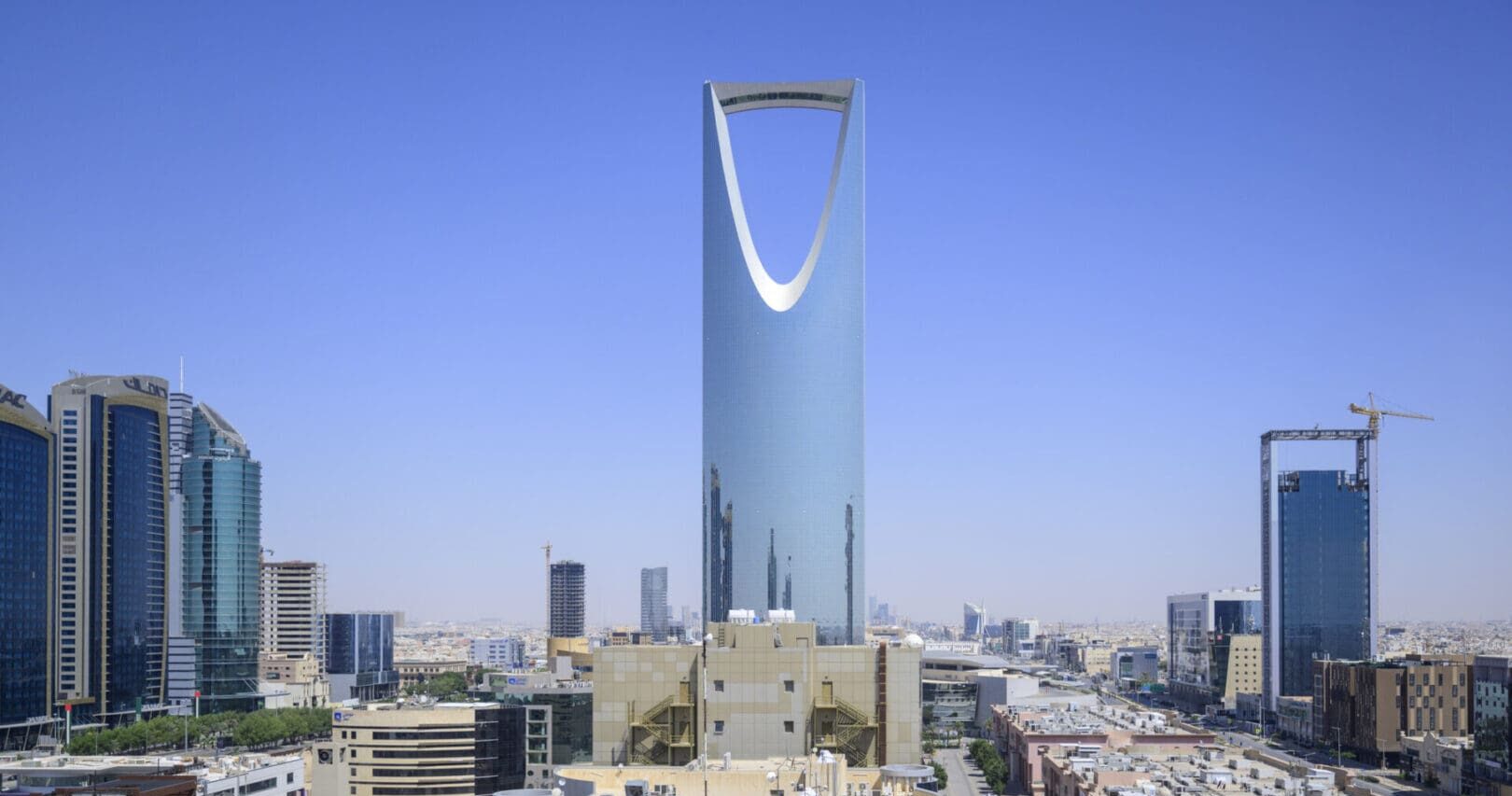 Al Olaya district of Riyadh, Saudi Arabia. Cityscape with Kingdom Center and Centrepoint Tower, central landmark with upside down parabolic arch against clear blue sky.