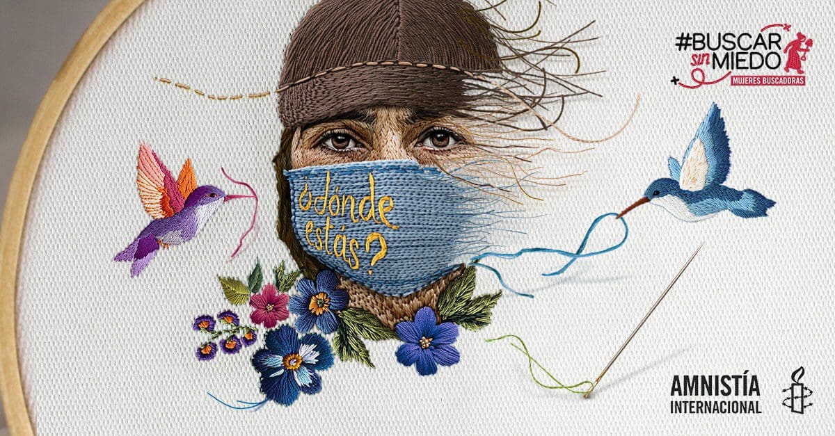 A close up photo of a needlepoint weaving of a woman's face wearing a mask that says 