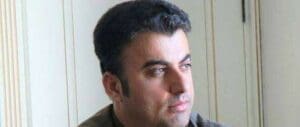 Light from a window falls on Sherwan Sherwani's face, which has a calm expression as he looks to his left.