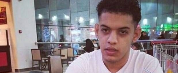 Jalal Labbad speaking in a large building with glass walls, wearing a white shirt and hair cut short on the sides and longer on the top.