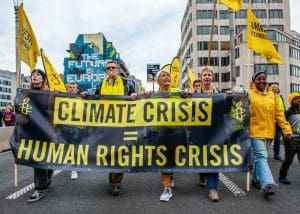 A group of people holding a protest banner that says 'Climate Crisis. Human Rights Crisis.'